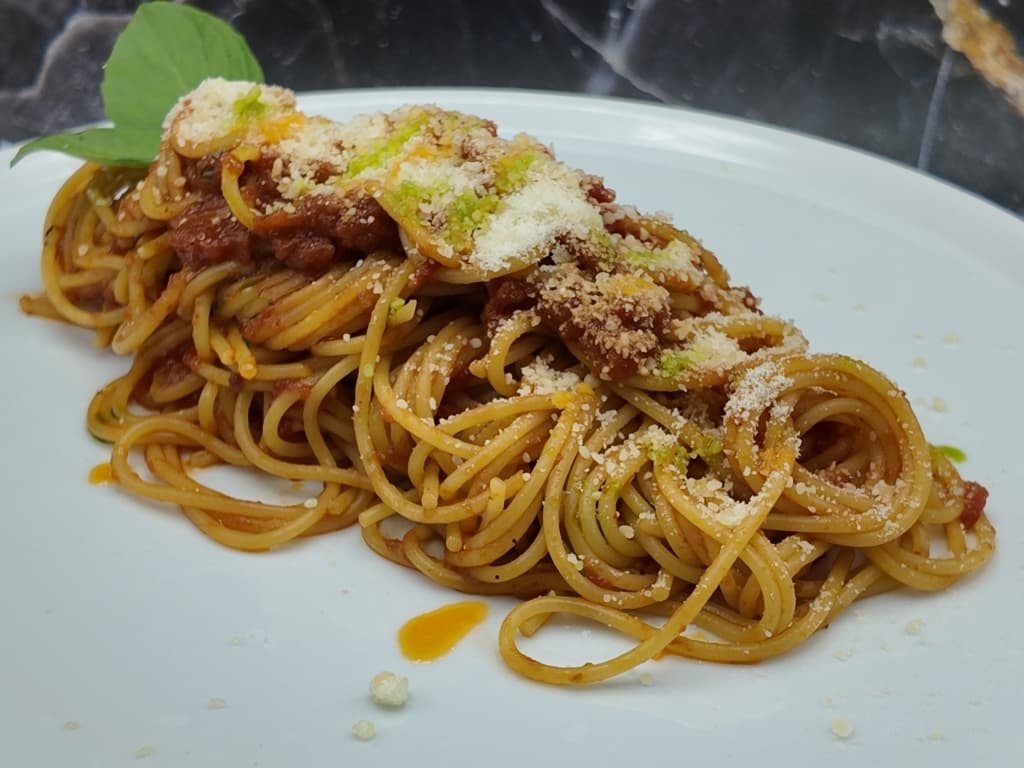 Spaghetti with cheese in tomato sauce and basil oil